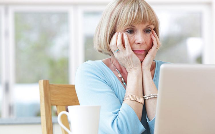 Rentnerin blickt besorgt auf ihren Laptop