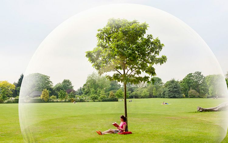 Eine junge Frau sitzt im Parkt und ist geschützt durch eine Glaskuppel
