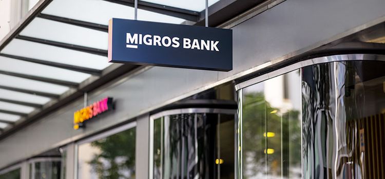Eingang der Migros Bank mit Leuchtschrift