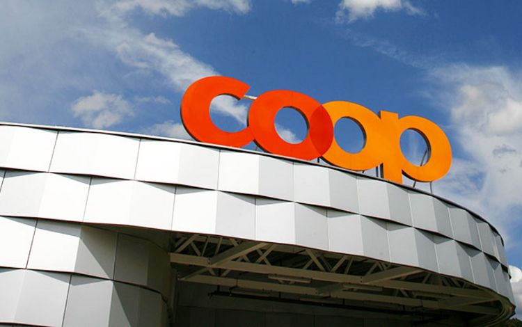 Coop-Logo auf Dach vor blauem Himmel