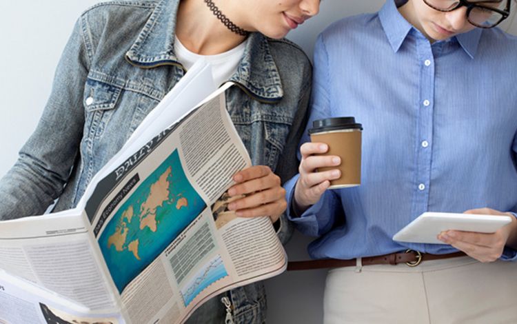 Zwei Frauen mit Zeitung und Tablet