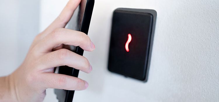 Hand mit Smartphone identifiziert sich für die Zutrittskontrolle in einem Gebäude
