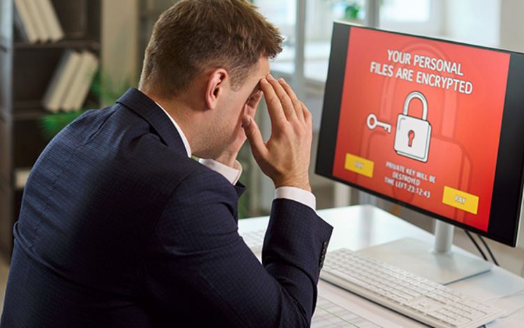 Geschäftsmann vor Monitor mit dem Hinweis, dass sein PC gehackt wurde