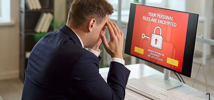 Geschäftsmann vor Monitor mit dem Hinweis, dass sein PC gehackt wurde