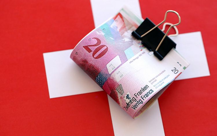 Ein Bündel 20er-Noten als Bargeld auf Schweizer Flagge