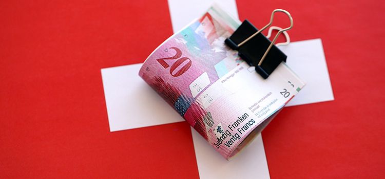 Ein Bündel 20er-Noten als Bargeld auf Schweizer Flagge