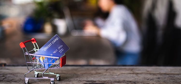 Miniatur-Einkaufswagen mit Kreditkarte auf einem Tisch