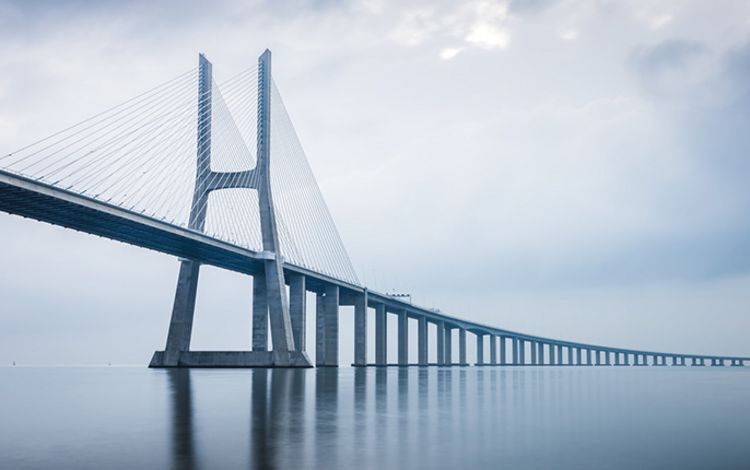 Die Vasco da Gama-Brücke spannt sich bei Sonnenaufgang über das Meer.