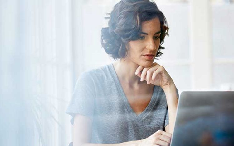 Junge Frau sitzt konzentriert vor ihrem Laptop