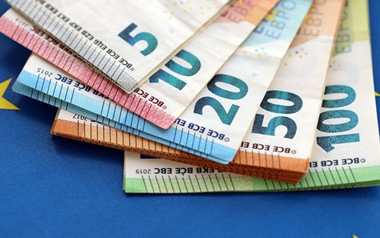 Euro-Banknoten als Fächer auf eine EU-Flagge