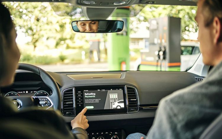 Eine Dame bedient in ihrem Auto über den Monitor das In-Car-Payment