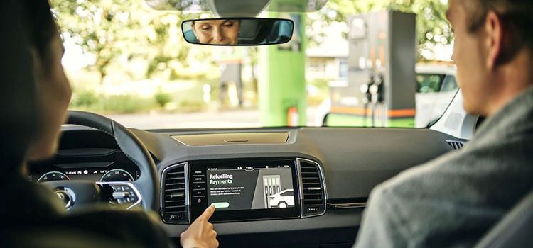 Eine Dame bedient in ihrem Auto über den Monitor das In-Car-Payment