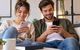 Junges Paar auf Sofa checkt auf den Smartphones ihre Vorsorge-Apps