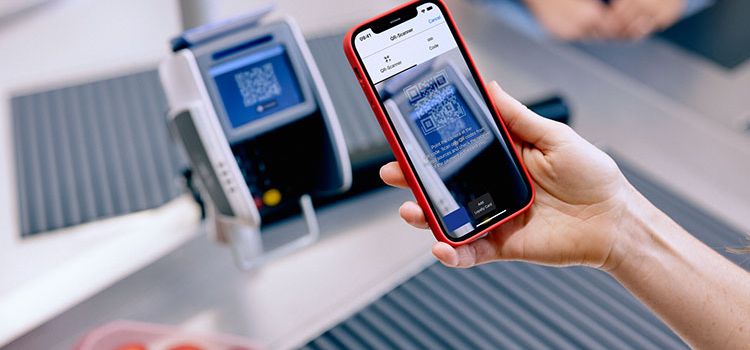 Frau mit Smartphone bezahlt an der Ladenkasse mit Twint