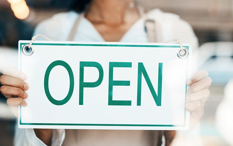 Schild in Schaufenster mit Aufschrift Open