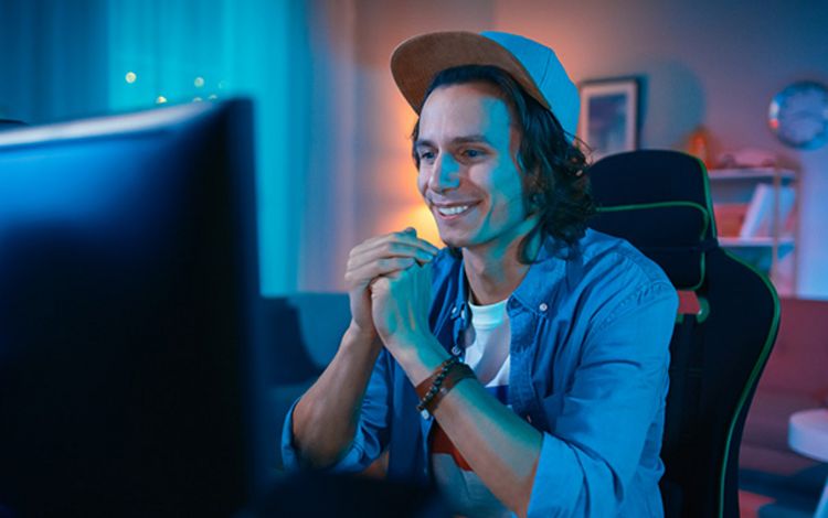 Junger Mann beim Aktienhandel am PC zu Hause