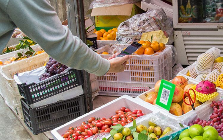 Mobile Zahlung mit WeChat, Hand mit Smartphone scannt einen QR-Code auf dem Markt