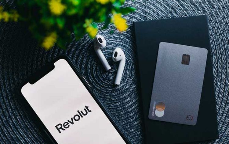 Smartphone mit Revolut-App und Debitkarte