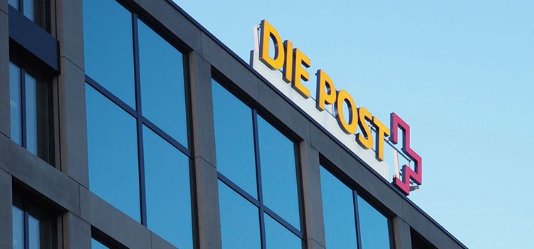 Hauptgebäude der Post mit Logo gegen blauen Himmel