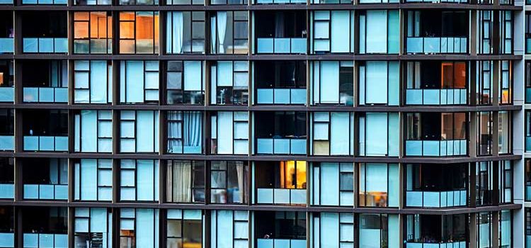 Fassade eines Wohnblocks mit teilweise erleuchteten Fenstern