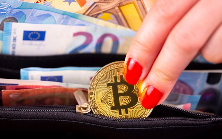 Eine Frau nimmt eine Bitcoin-Münze aus der Brieftasche