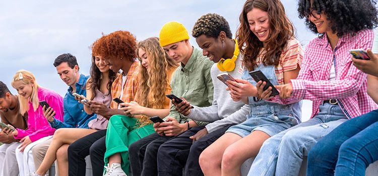 Viele junge Menschen nebeneinander, alle lachen und sind mit ihrem Smartphone beschäftig