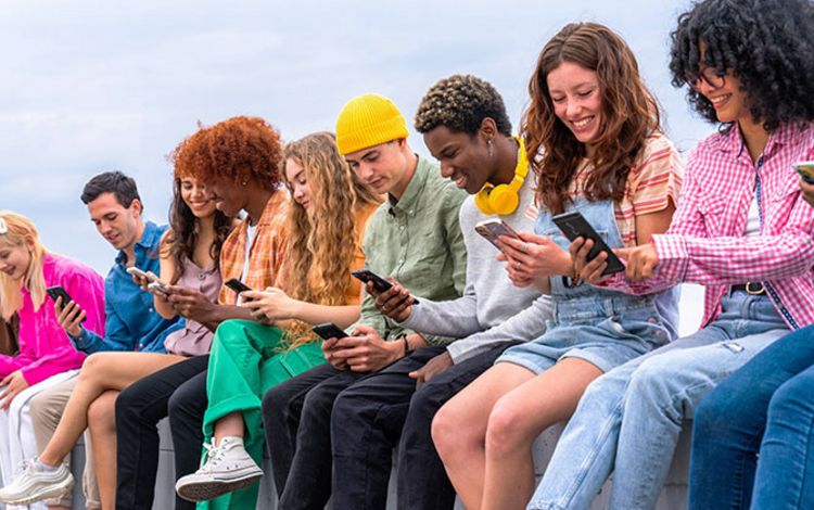 Viele junge Menschen nebeneinander, alle lachen und sind mit ihrem Smartphone beschäftig