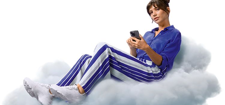 Junge Frau mit Smartphone sitzt auf einer Wolke