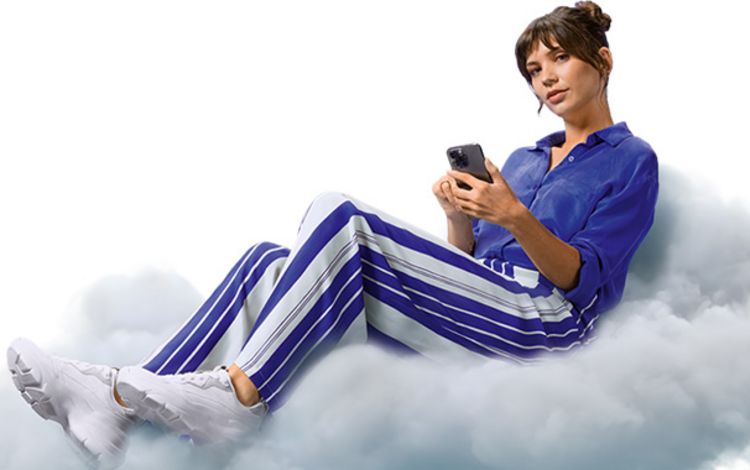 Junge Frau mit Smartphone sitzt auf einer Wolke