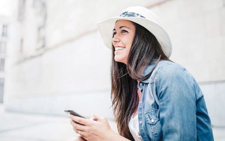 Junge Frau mit Hut und Smartphone