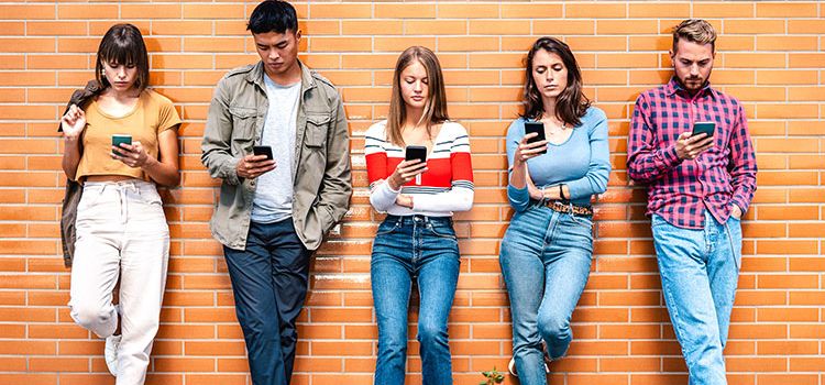 Junge Menschen der Generation Z, alle mit ihrem Handy beschäftigt