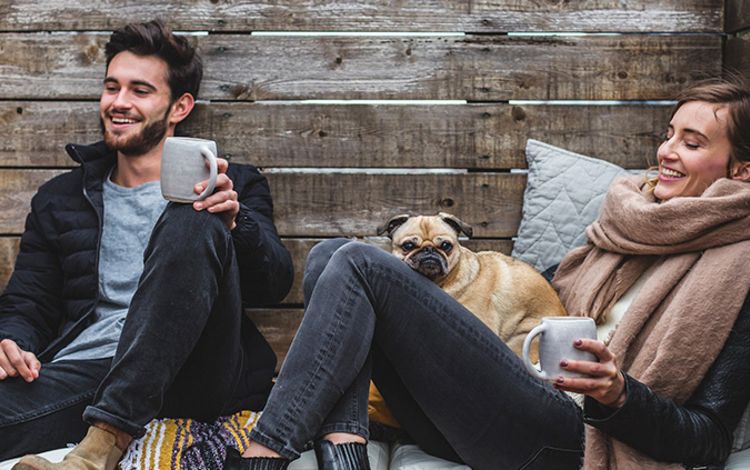 Junges Paar mit Hund, entspannt beim Kaffeetrinken