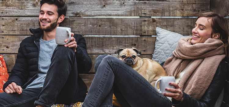 Junges Paar mit Hund, entspannt beim Kaffeetrinken