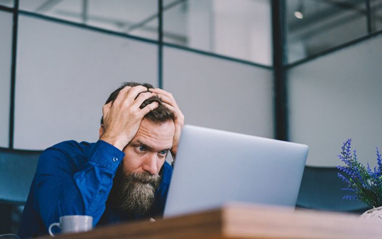 Junger Mann vor Laptop, der verzweifelt scheint