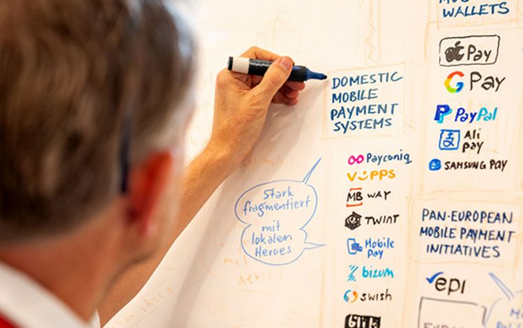 Mann schreibt und illustriert eine Tafel am Swiss Payment Forum