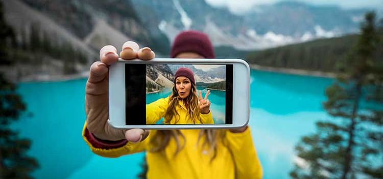 Junge Frau macht in den Bergen ein Selfie mit ihrem iPhone