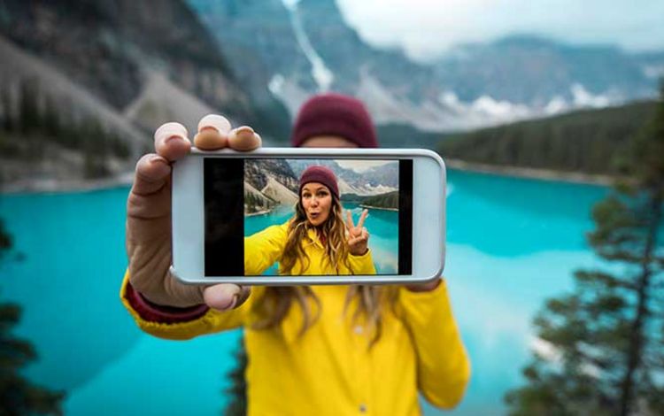 Junge Frau macht in den Bergen ein Selfie mit ihrem iPhone