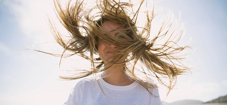 Junge Frau steht im Wind, der ihr die Haare zerzaust