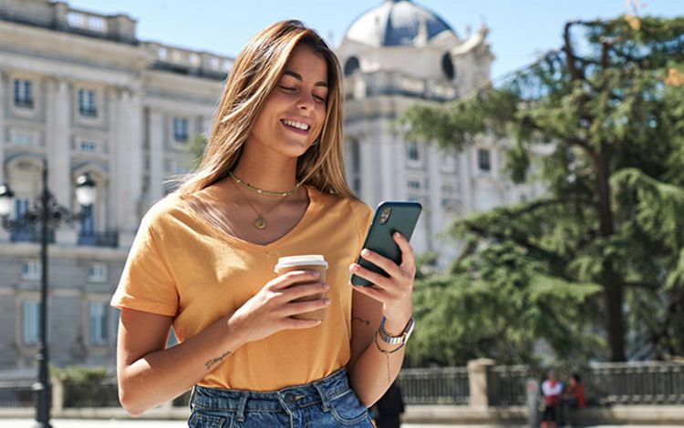 Junge Frau im Urlaub, die ihr Handy checkt