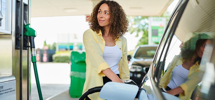 Junge Frau an betankt ihr Auto an der Tankstelle