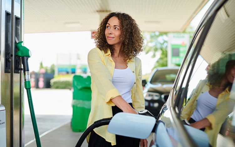 Junge Frau an betankt ihr Auto an der Tankstelle