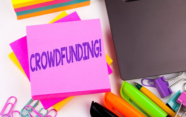 Schreibtisch mit Zettel mit Aufschrift Crowdfunding
