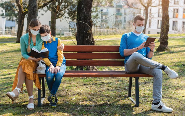 Menschen mit Schutzmasken auf Parkbank