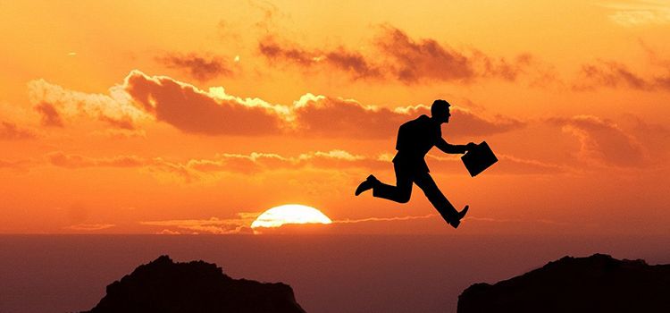 Ein Banker überspringt eine Schlucht im Sonnenuntergang