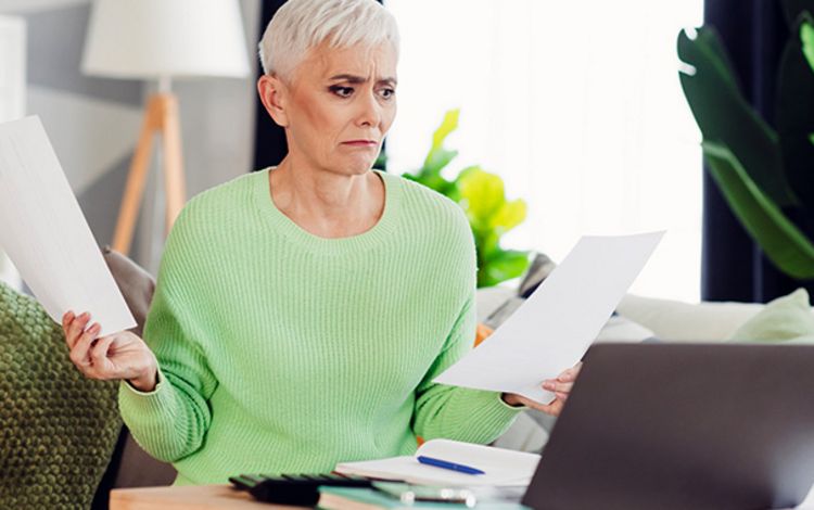 Frau checkt am Laptop Papiere und Dokumente