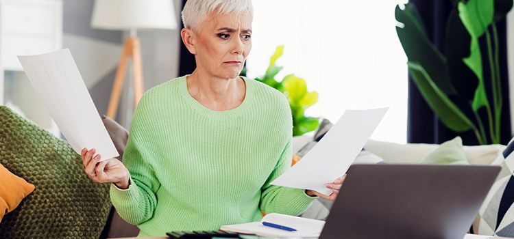 Frau checkt am Laptop Papiere und Dokumente