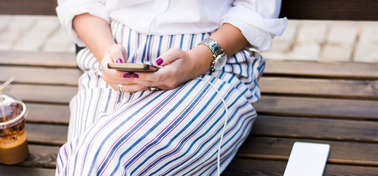 Junge Frau mit Smartphone auf Parkbank