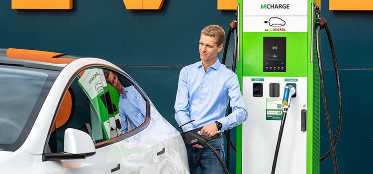 Junger Mann mit Auto an E-Ladestation