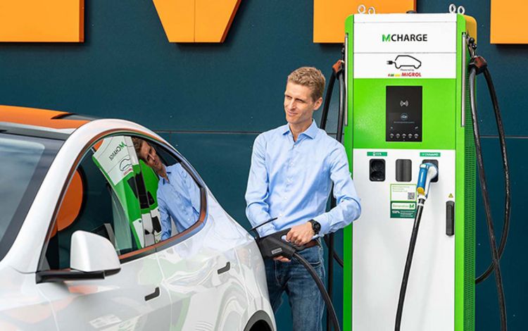 Junger Mann mit Auto an E-Ladestation