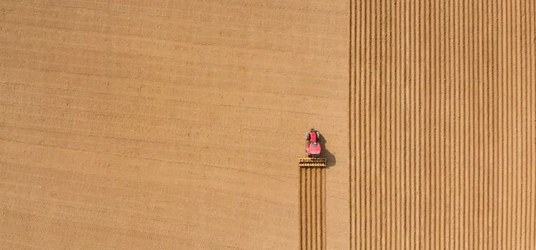 Luftaufnahme eines Traktors, der einen Acker pflügt